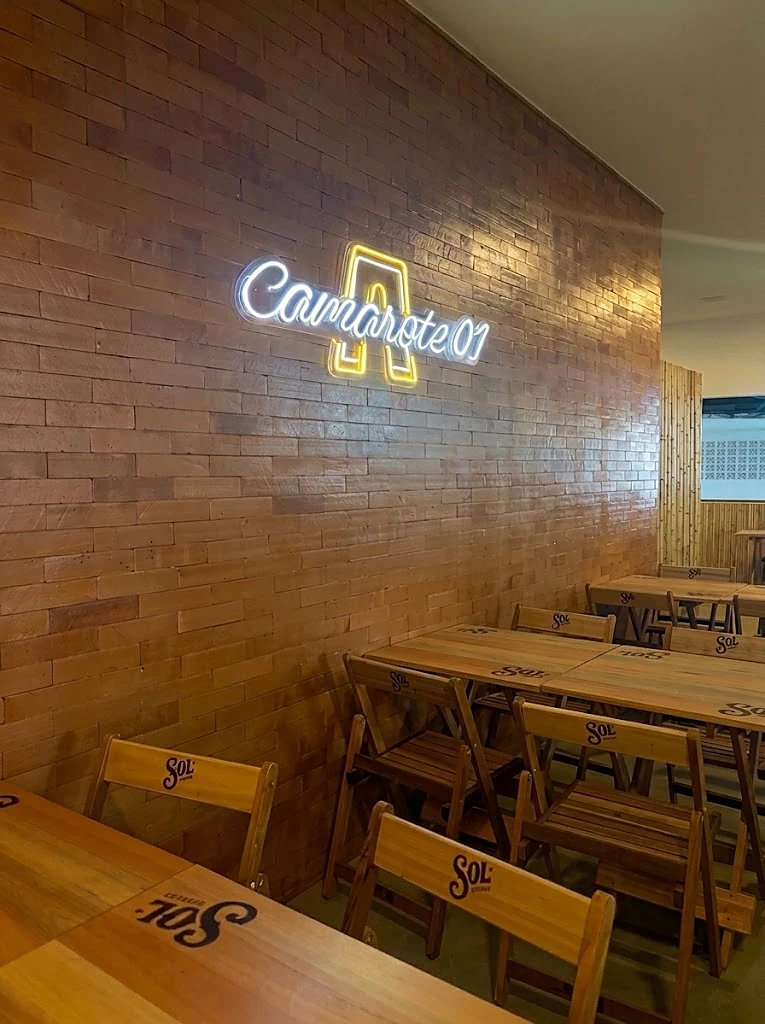 O Camarote 01, com o letreiro em neon e as mesas de madeira
